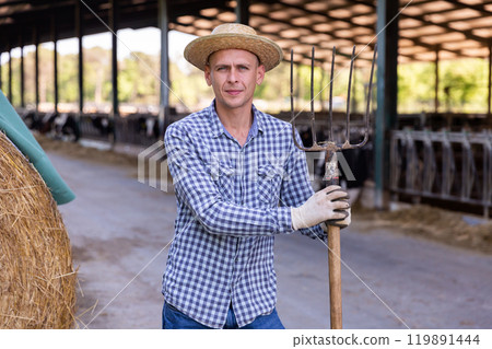 Confident owner of dairy farm standing on background with cows in stall 119891444