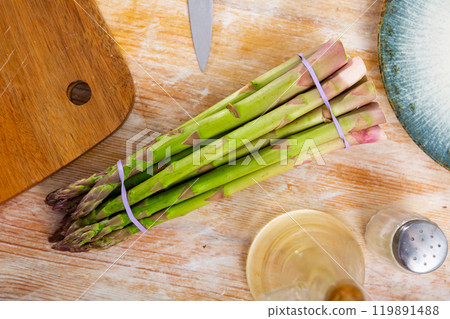 Bunch of fresh asparagus on table with knife and olive oil Bunch of fresh asparagus on table with knife and olive oil 119891488
