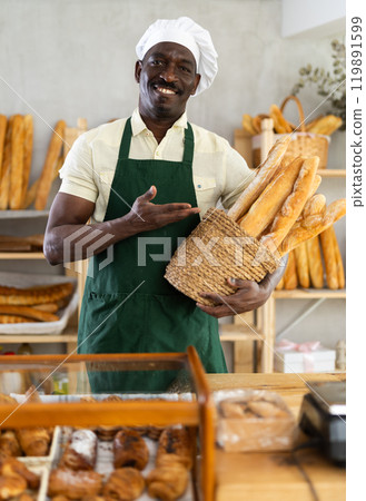 Male baker with basket of fresh baguettes 119891599
