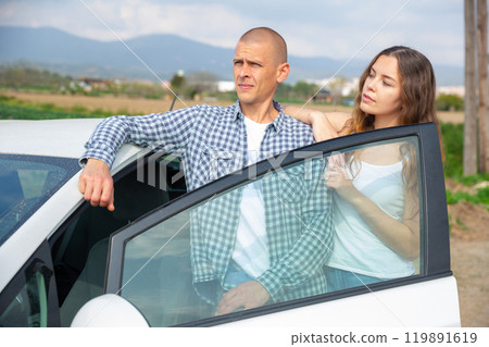 Positive young couple talking near car on spring day Positive young couple talking near car on spring day 119891619