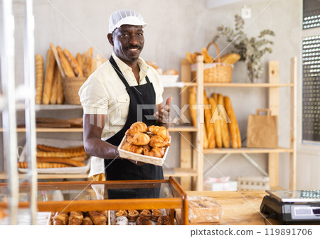 Male baker holding a tray of freshly baked croissants Male baker holding a tray of freshly baked croissants 119891706