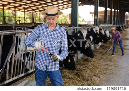 Male farmer standing with syringe at farm 119891716