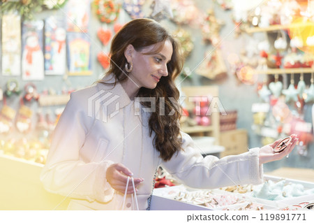Smiling woman choosing festive home decorations on street Christmas fair 119891771