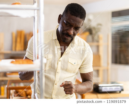 Male customer in casual clothes chooses croissants for breakfast in bakery 119891879