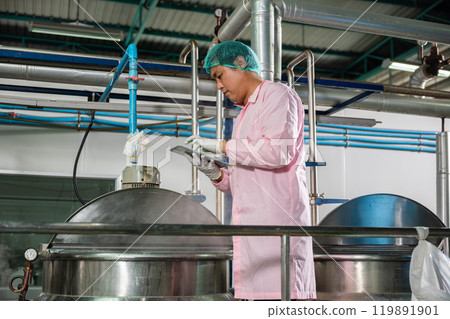 Worker using tablet in beverage factory oversees soda water filling while an engineer ensures precise quality control. Maintaining high industry standards in bottle manufacturing is paramount. 119891901