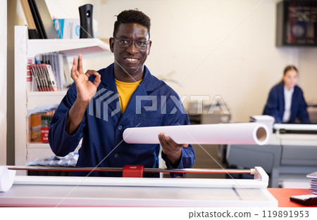 Happy middle-aged African American man in a blue robe uniform holding whatman in a roll in the typography 119891953
