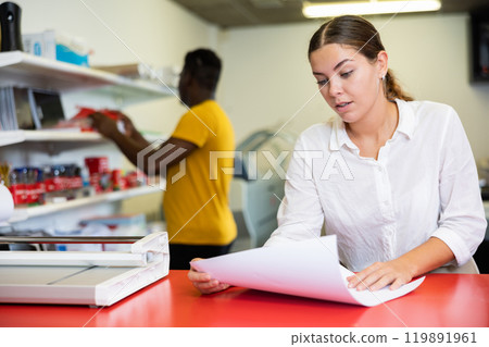 Portrait of an attentive woman checking quality of printing in printing house 119891961
