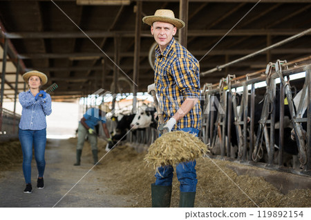 Male farmer working on dairy farm in cowshed 119892154