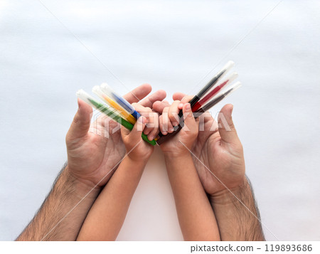 Family bond. Adult and child hands holding colorful paint tubes together 119893686