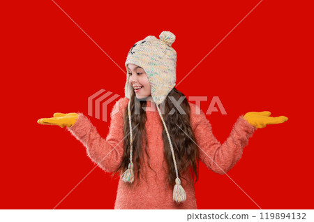 Childhood winter memories. Teen girl kid isolated on red studio. Child winter fashion. Girl enjoying winter style. Teen girl wearing stylish new year hat. Casual cool 119894132