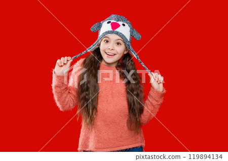 Knitted sweater and beanie hat. Trendy fashion outfit in winter. Winter girl child. Style portrait of teen girl in warm clothing and winter hat isolated on red. Happy New Year Knitted sweater and beanie hat. Trendy fashion outfit in winter. Winter girl child. Style portrait of teen girl in warm clothing and winter hat isolated on red. Happy New Year 119894134