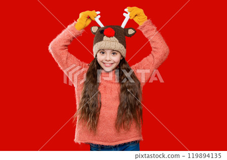 Childhood lifestyle. Winter child wardrobe. Teenage girl in Xmas hat isolated on red. Winter fashion for teenage style. Girl in knitted hat in winter season. Knitted earflap hat 119894135