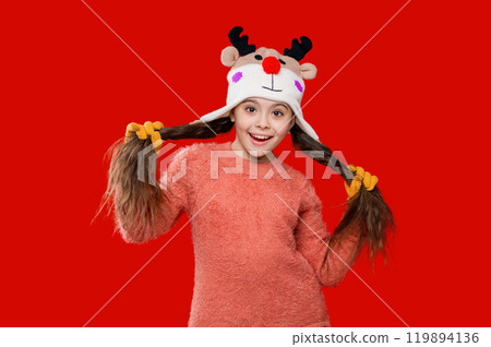 Girl in knitted hat in winter season. Childhood lifestyle. Winter child wardrobe. Teenage girl in Xmas hat isolated on red. Winter fashion for teenage style. Having true fun 119894136