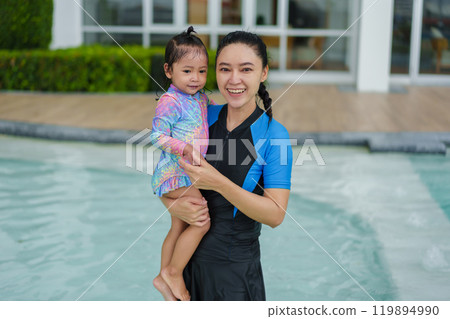 happy mother holding baby in her arms while playing in swimming pool 119894990