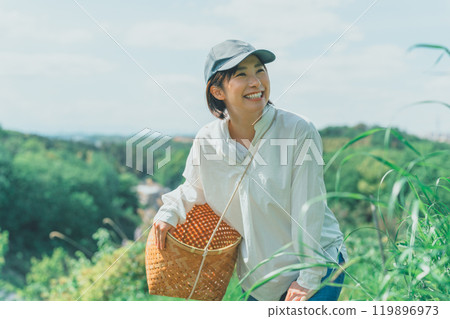 Young woman carrying a harvest basket in the mountains 119896973