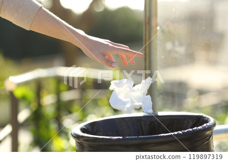 Hand throwing litter into bin in a park Hand throwing litter into bin in a park 119897319