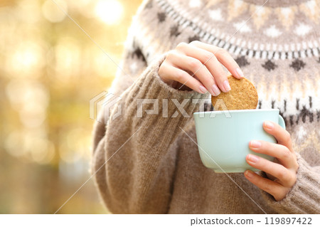 Woman dipping cookie in a coffee mug in autumn 119897422