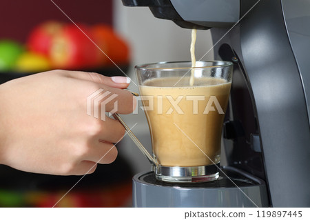 Woman hand holding a cup in a coffee maker 119897445
