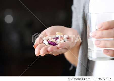 Woman hand holding a lot of pills and a glass 119897446