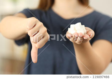 Woman hand holding sugar cubes with thumbs down 119897466