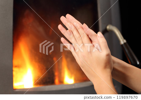Woman hands heating in front a fire place Woman hands heating in front a fire place 119897670