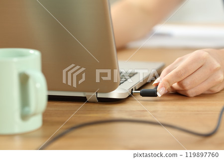 Woman plugging charger in a laptop 119897760