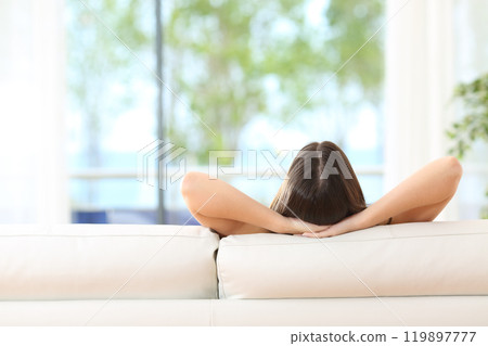 Woman relaxing on a couch at home Woman relaxing on a couch at home 119897777