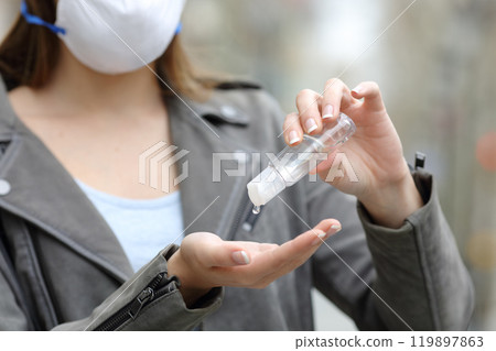 Woman with protective mask sanitizing hands 119897863