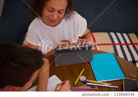Woman and child learning together with tablet and notebooks Woman and child learning together with tablet and notebooks 119898346
