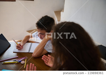 Boy studying at home while woman helps with homework 119898361