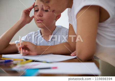 Mother helping son with homework at kitchen table Mother helping son with homework at kitchen table 119898394