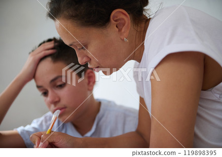 Mother helping son with homework at home in study session Mother helping son with homework at home in study session 119898395