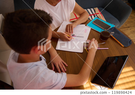 Mother helping child with homework at cozy home setting Mother helping child with homework at cozy home setting 119898424
