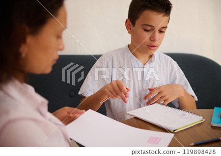 Mother and son engaged in a focused homeschool lesson Mother and son engaged in a focused homeschool lesson 119898428