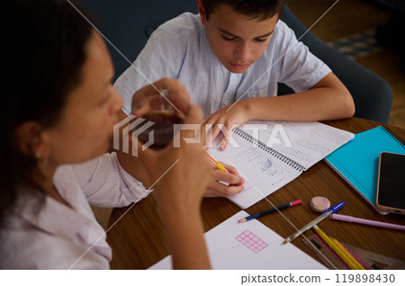 Young student doing homework with guidance from adult Young student doing homework with guidance from adult 119898430