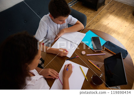 Mother and son studying together at home at a wooden table Mother and son studying together at home at a wooden table 119898434