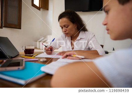 Mother and son focused on study at home with notebooks Mother and son focused on study at home with notebooks 119898439