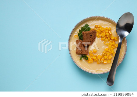 Corn soup in a plate, on a blue background. Corn soup in a plate, on a blue background. 119899094