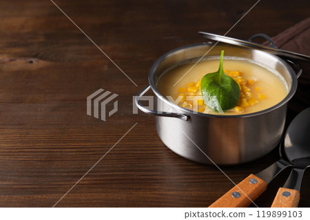 Corn soup in a pot, on a brown background. 119899103