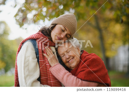 Portrait of a granddaughter on an autumn walk in the park with her grandmother. Portrait of a granddaughter on an autumn walk in the park with her grandmother. 119899416