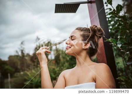 Portrait of a beautiful woman standing in a garden, holding a ornamental grass in her hand. Mental well-being and connection with nature. Portrait of a beautiful woman standing in a garden, holding a ornamental grass in her hand. Mental well-being and connection with nature. 119899470