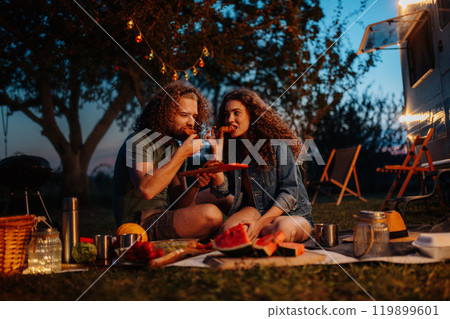 Couple having romantic picnic during camping trip in nature. Caravan traveling for young people. 119899601