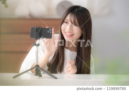 Image of a video distributor: A cute young woman waving at the camera 119899780