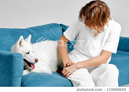 Woman and Husky Relaxing on Blue Sofa Woman and Husky Relaxing on Blue Sofa 119900608