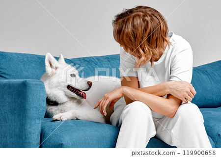 Woman and Husky Sharing a Happy Moment on Blue Sofa 119900658
