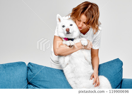Woman Hugging Her White Husky with Love 119900696