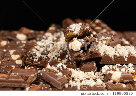 Pieces of broken organic milk chocolate with nuts and raisins. Healthy sweets Pieces of broken organic milk chocolate with nuts and raisins. Healthy sweets 119900850
