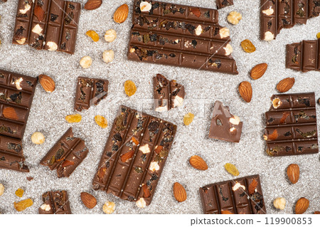 Broken chocolate pieces with nuts and raisins on a stone background top view Broken chocolate pieces with nuts and raisins on a stone background top view 119900853