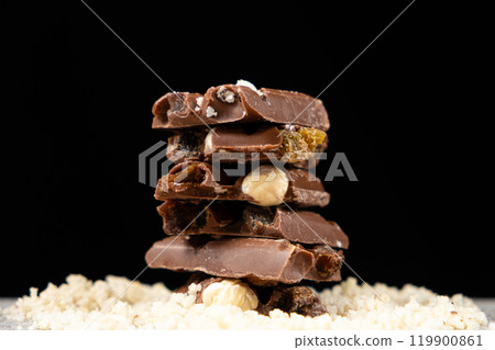 Pieces of milk nut chocolate on a black background. Pieces of milk nut chocolate on a black background. 119900861