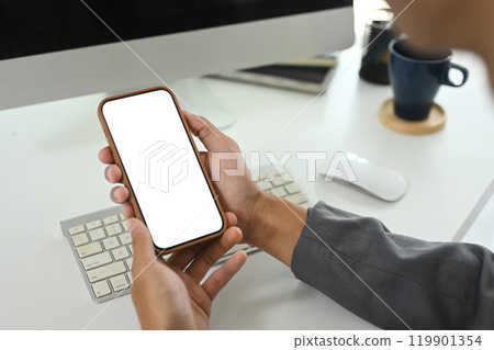 Close up of unrecognizable businessman holding a smartphone with white screen Close up of unrecognizable businessman holding a smartphone with white screen 119901354